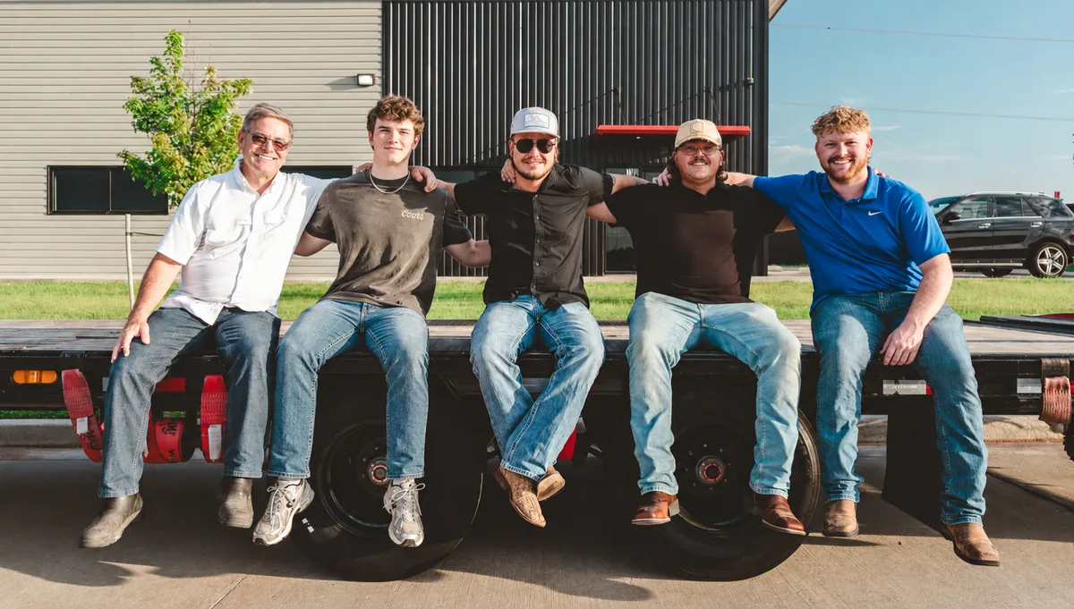 The Colby Transport crew seated on a flatbed deck outside the terminal.