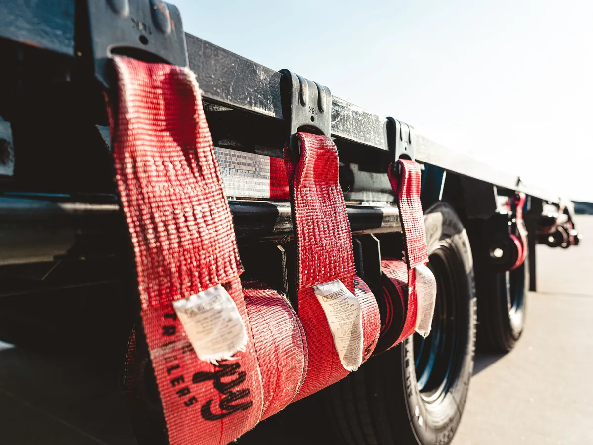 Ratchet straps staged along the rail of a Colby Transport flatbed.